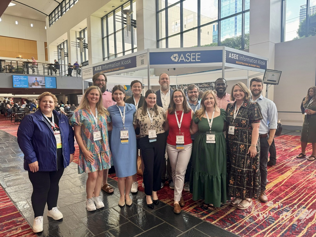 A large group of Louisiana Tech faculty and students posing together in the conference exhibit hall.