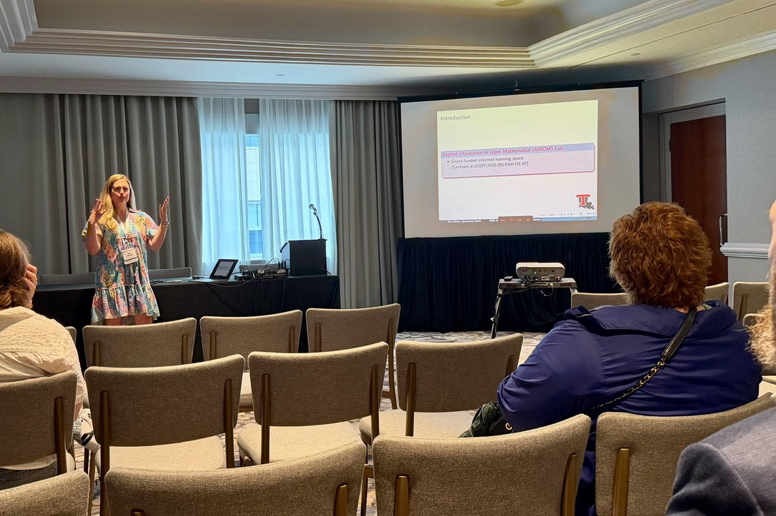 Ann presenting slides on the AXIOM Lab to a seated audience.