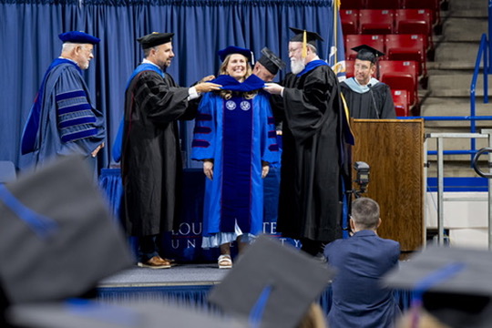 Ann being hooded on stage during her PhD graduation ceremony.